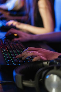 Close-up of hands typing on an RGB keyboard during a gaming session with headphones nearby.