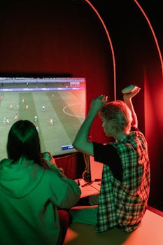 Two teenagers enthusiastically playing video games on a console in a cozy room.